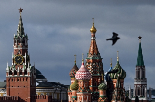 A pigeon flies in front of the Kremlin's Spasskaya tower (L) and Saint Basil's cathedral (C) in Moscow on March 1, 2023. (Photo by Kirill KUDRYAVTSEV / AFP)